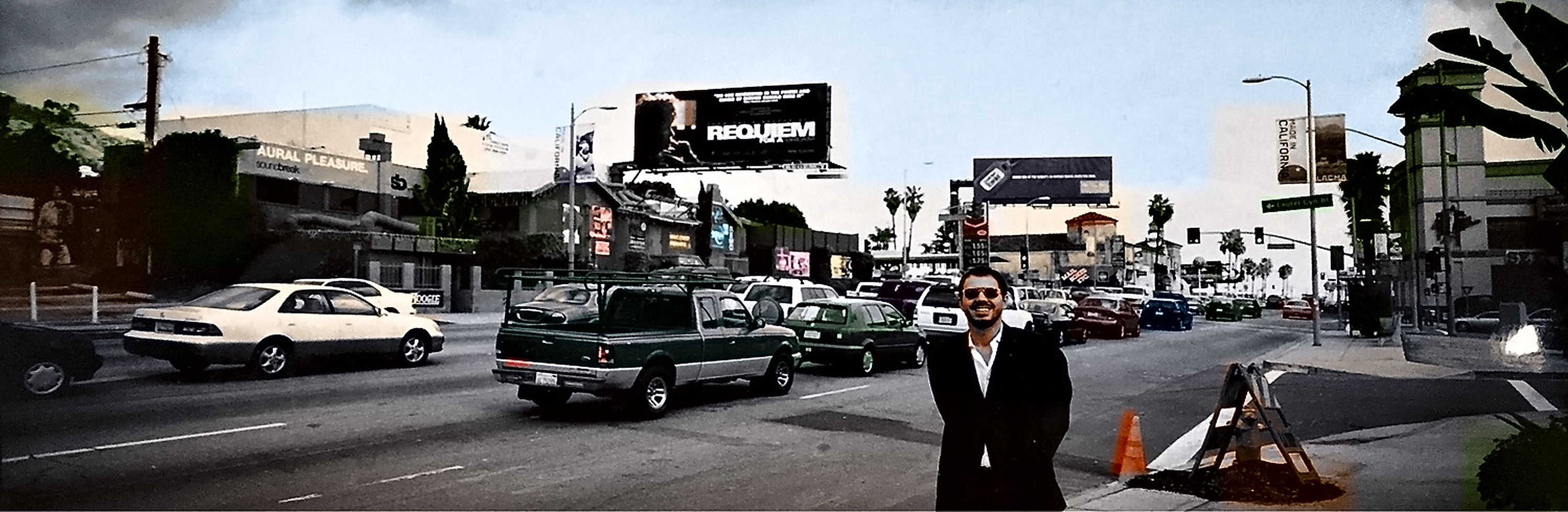 Sunset Boulevard at Argyle, traffic in the foreground and a Requiem for a Dream billboard above the street. M. Scott Vogel stands at the kerb.